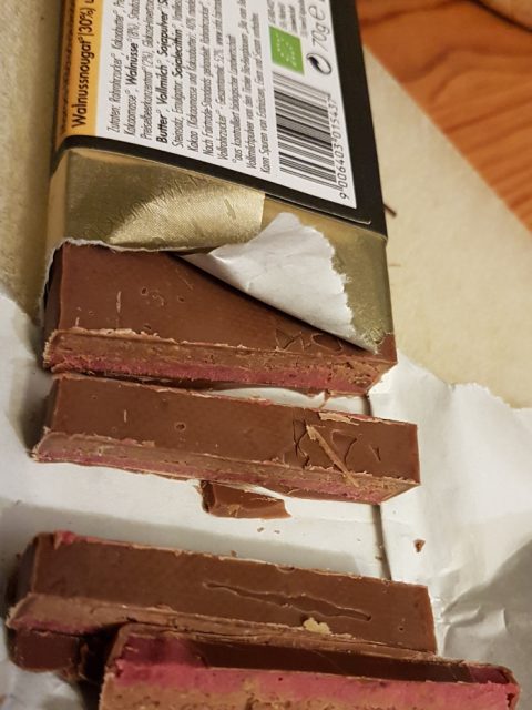 Bild einer geöffneten Tafel Schokolade mit geschnittenen Stückchen davor